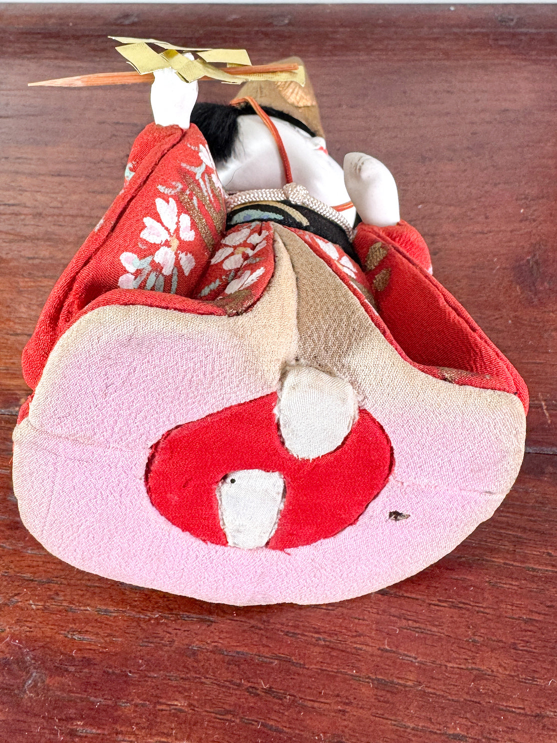 Poupée japonaise Kimekomi en kimono rouge avec chapeau doré et bâton rituel shintō, vu de dessous
