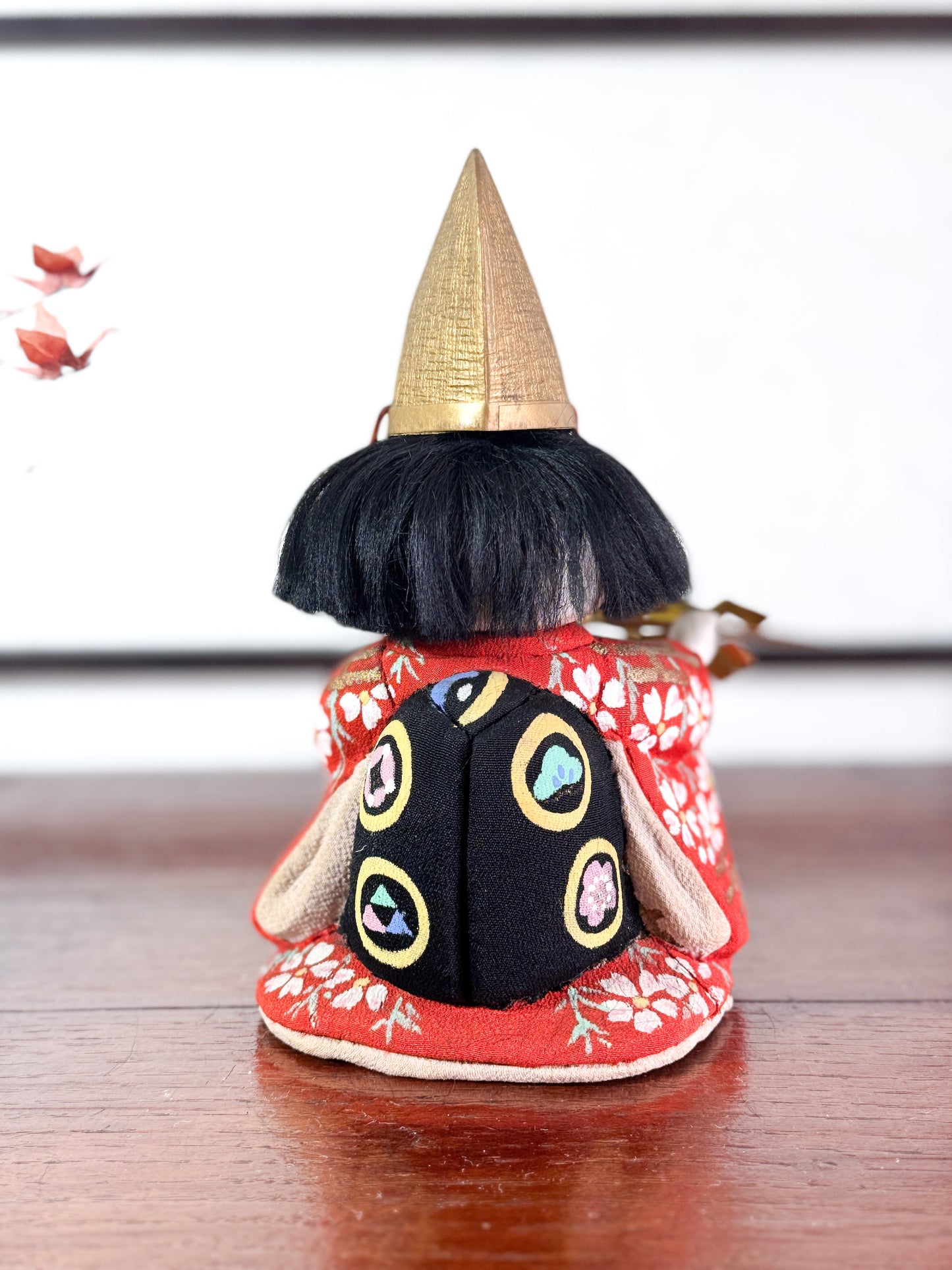 Poupée japonaise Kimekomi en kimono rouge avec chapeau doré et bâton rituel shintō, vu de dos