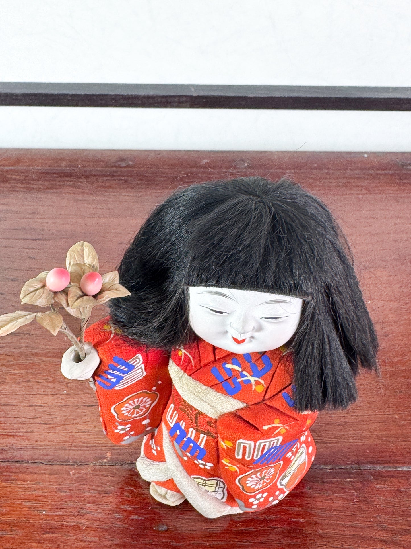 poupée japonaise en kimono rouge avec bouquet de fleurs, vu de dessus