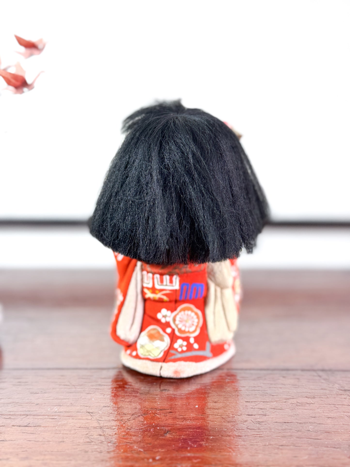 poupée japonaise en kimono rouge avec bouquet de fleurs, vu de dos