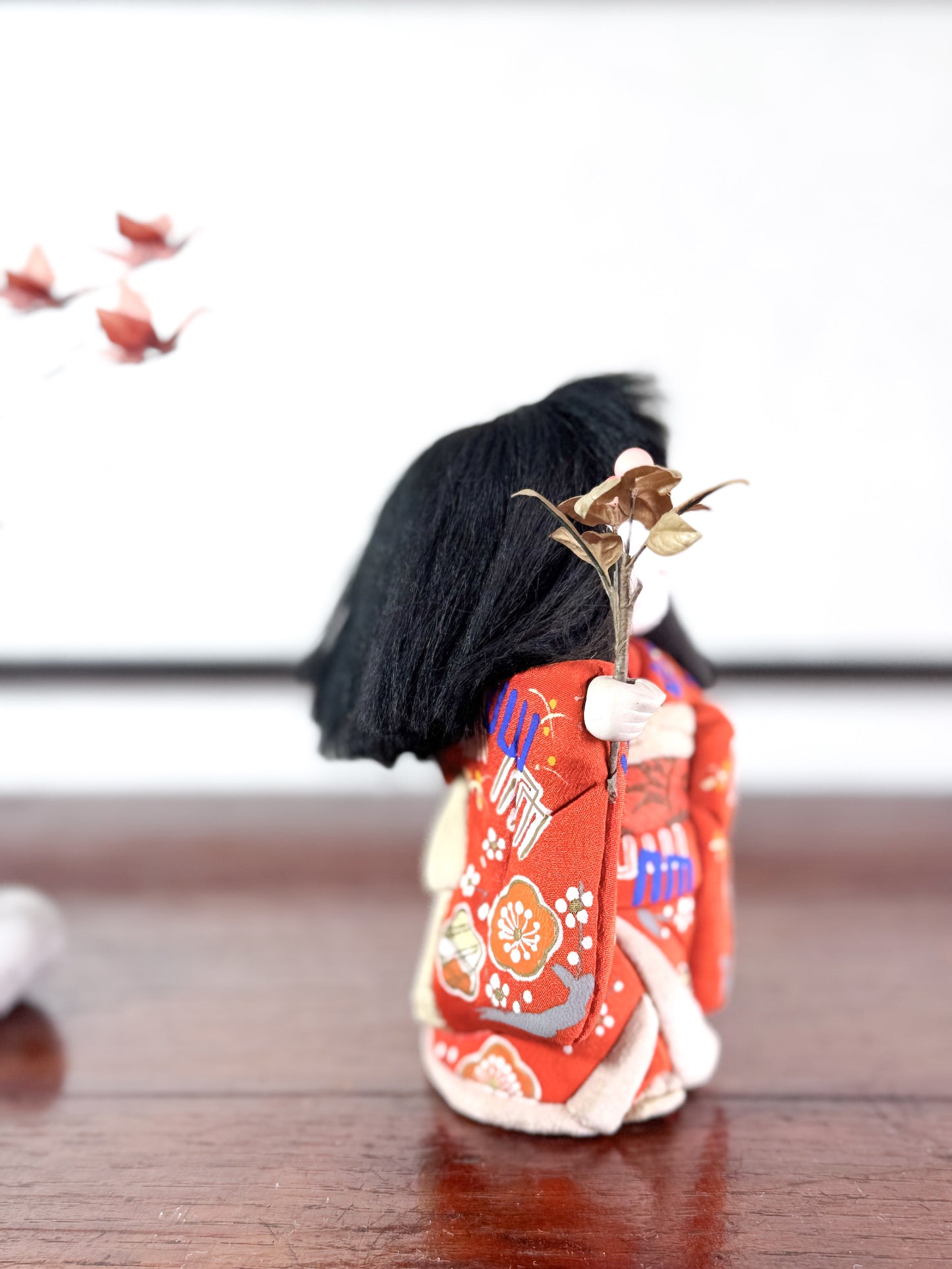 poupée japonaise en kimono rouge avec bouquet de fleurs, le profil droit