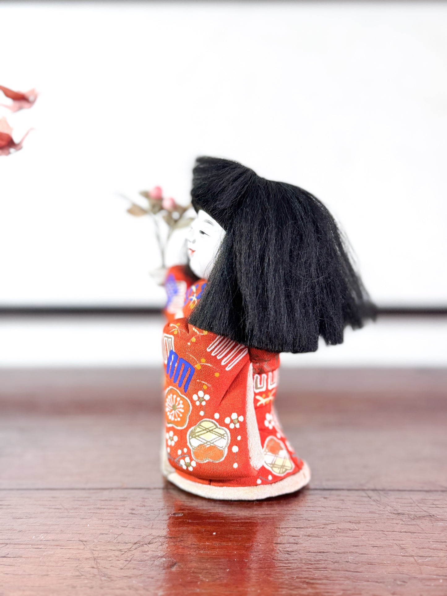 poupée japonaise en kimono rouge avec bouquet de fleurs, le profil gauche