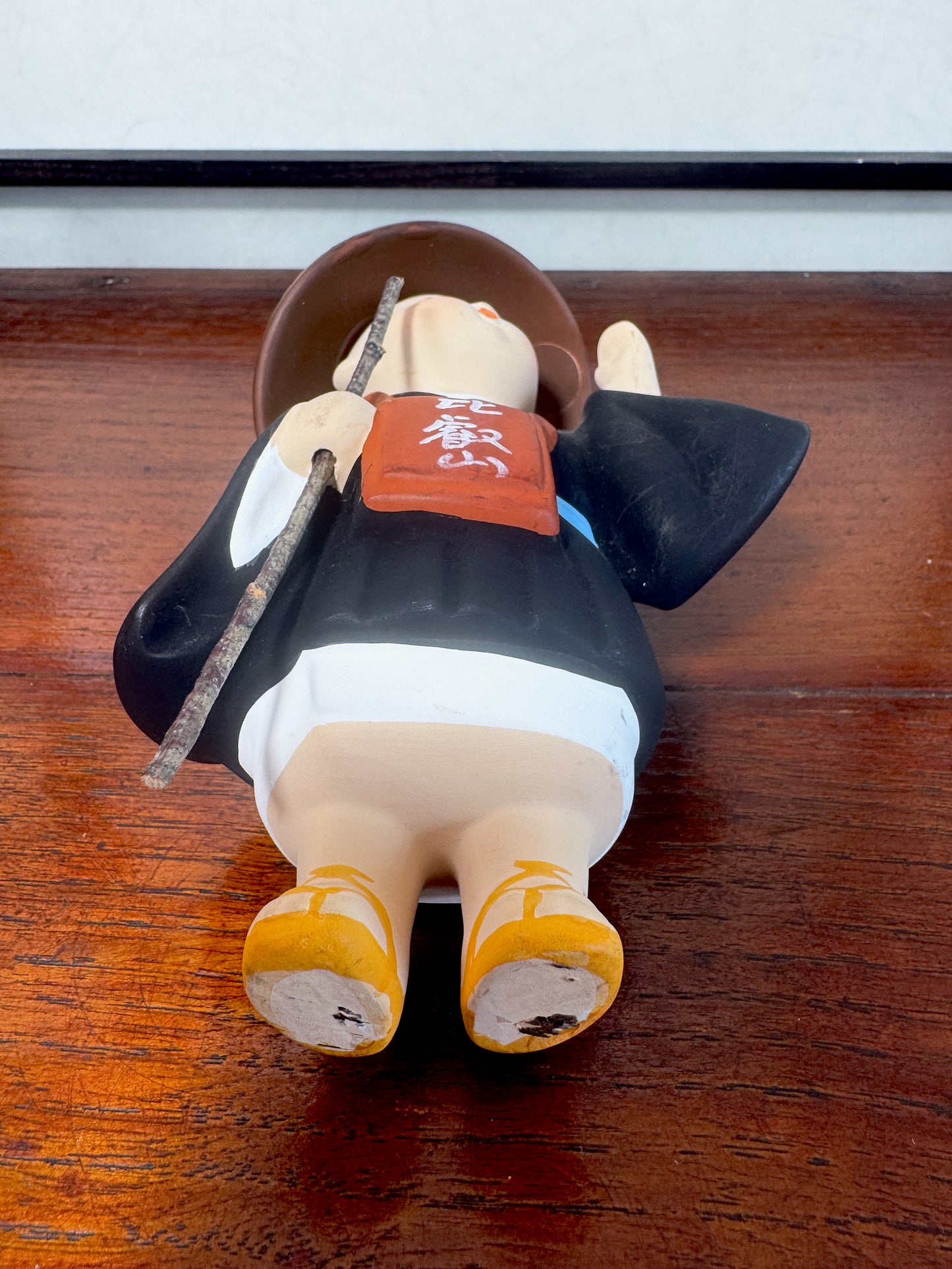 statuette enfant pèlerin en céramique japonaise avec chapeau et bâton, vu de dessous