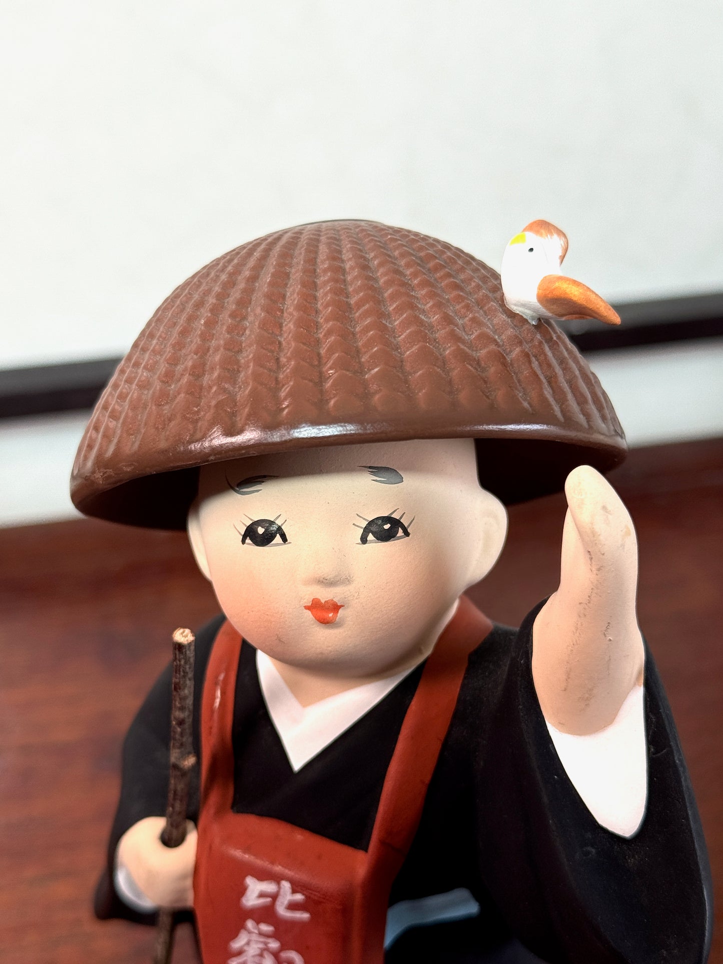 statuette enfant pèlerin en céramique japonaise avec chapeau et bâton, gros plan sur le visage