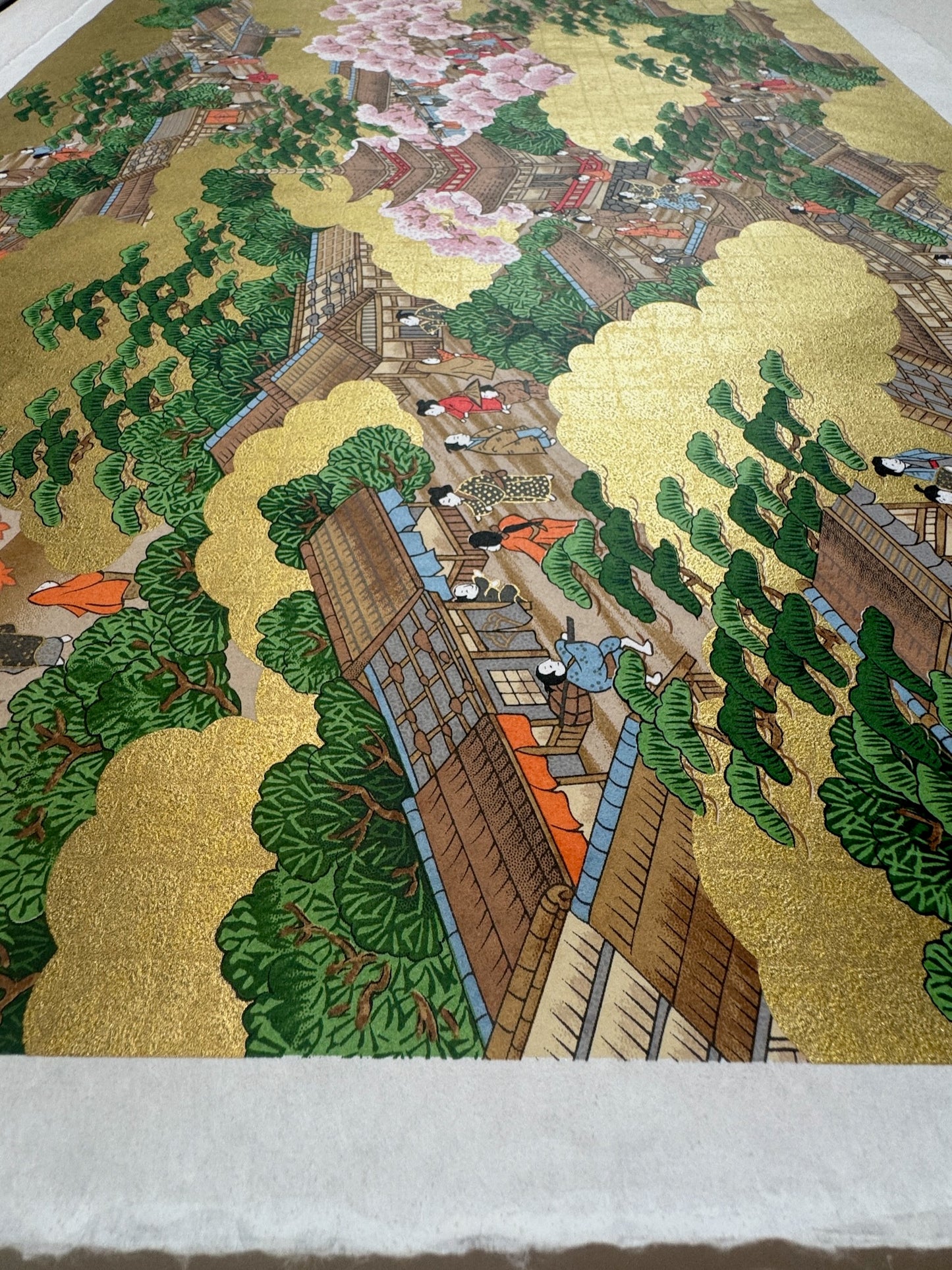 Sérigraphie Japonaise automne et printemps dans un village. Scène de vie avec personnages, maisons traditionnelles. Brillance du fond or.