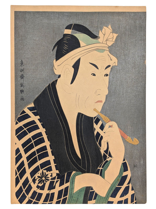 Estampe japonaise de Sharaku Toshusai d'un acteur de Kabuki fumant la pipe. Kimono à carreaux bleu marine. Il semble chercher un objet dans sa manche. Fond micacé argenté typique de cet artiste.