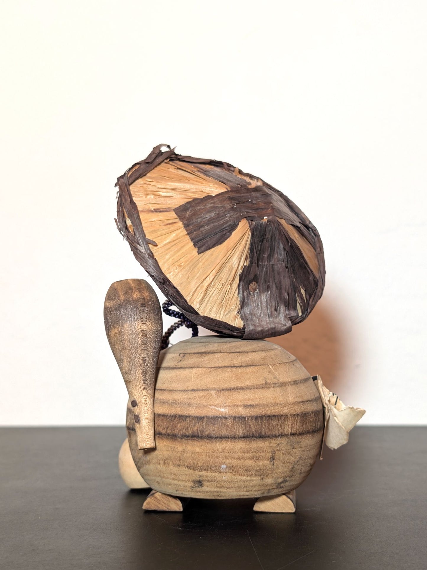 Tanuki en bois avec chapeau, bouteille de saké et bébé tanuki, sculpture japonaise artisanale symbolisant chance et prospérité, vu de dos