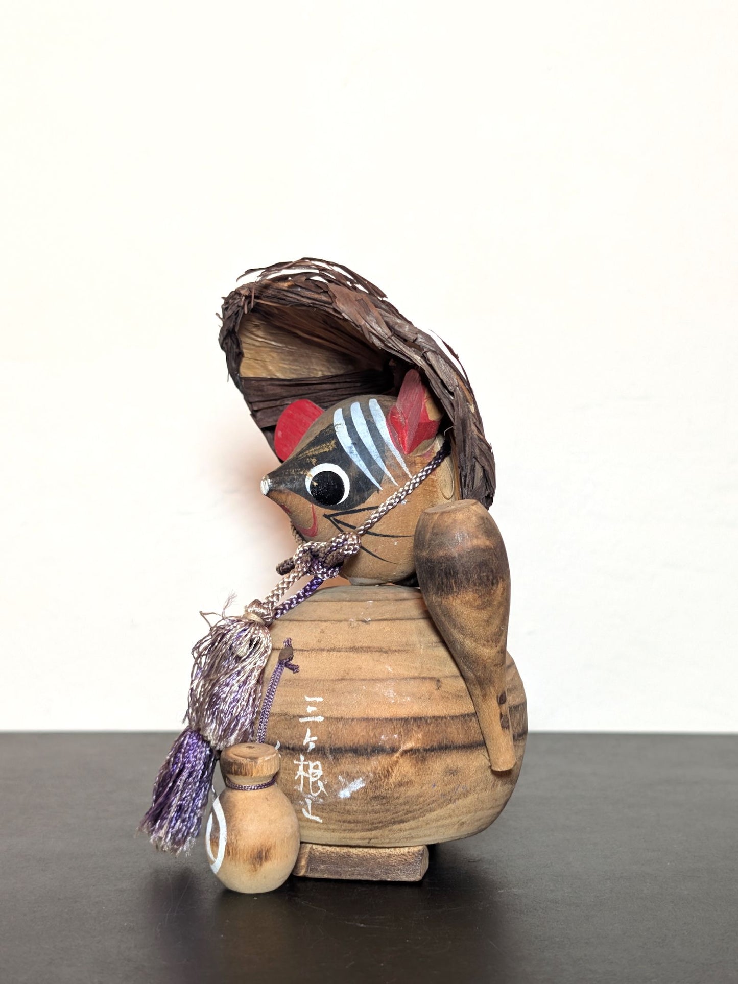 Tanuki en bois avec chapeau, bouteille de saké et bébé tanuki, sculpture japonaise artisanale symbolisant chance et prospérité, profil gauche