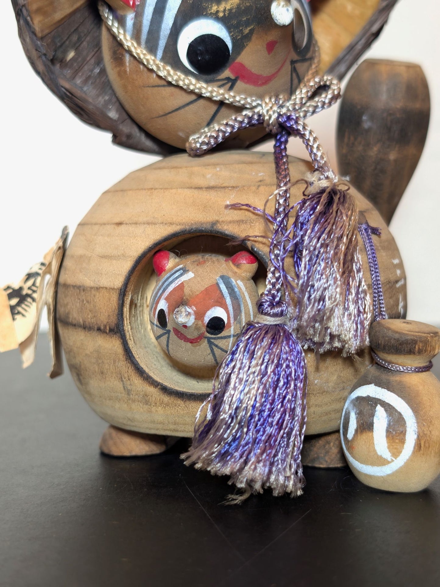 Tanuki en bois avec chapeau, bouteille de saké et bébé tanuki, sculpture japonaise artisanale symbolisant chance et prospérité, gros plan sur le bébé