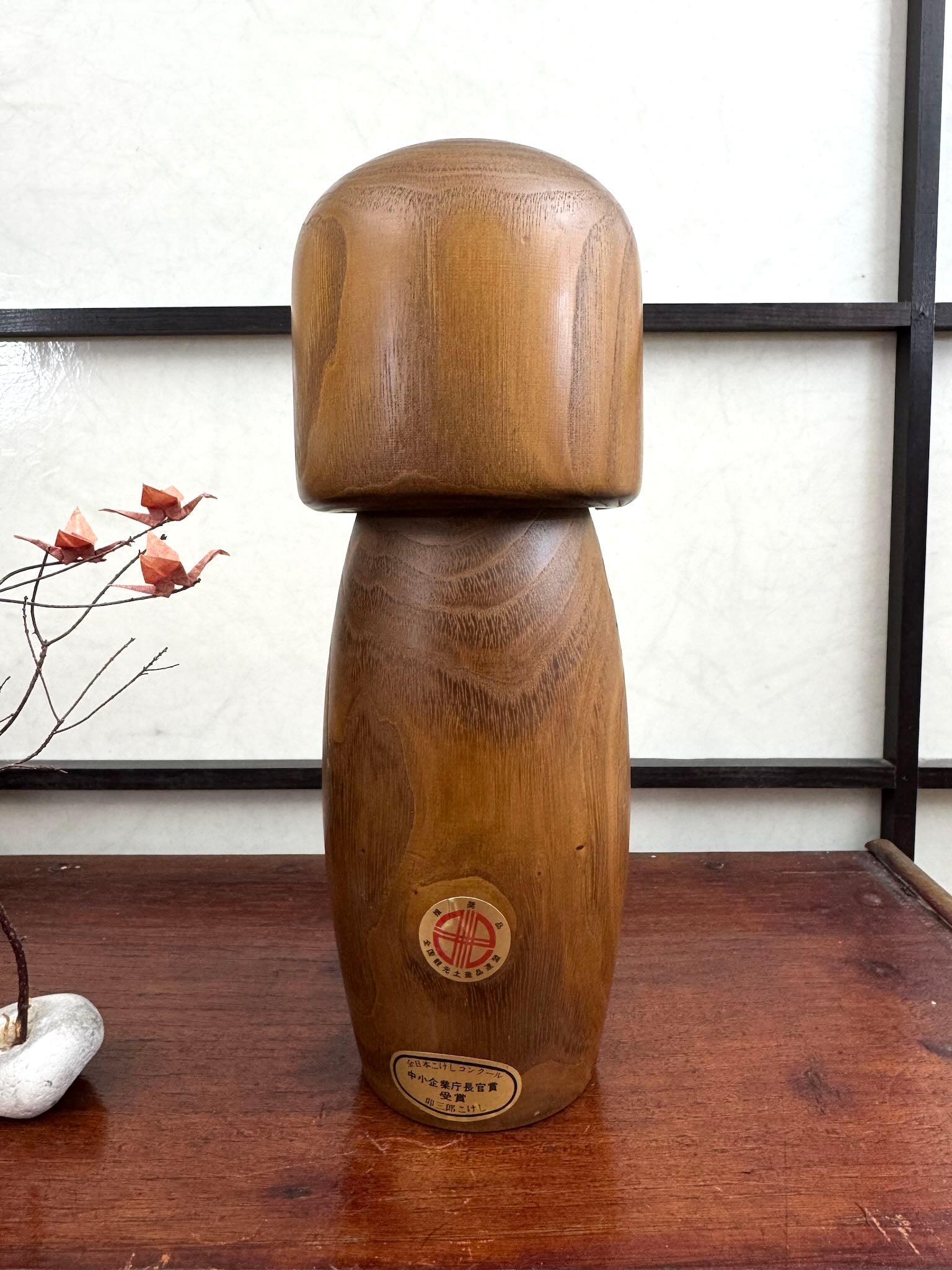 kokeshi fleur de prunier de Usaburo sur bois blond, vu de dos avec étiquette de prix remporté