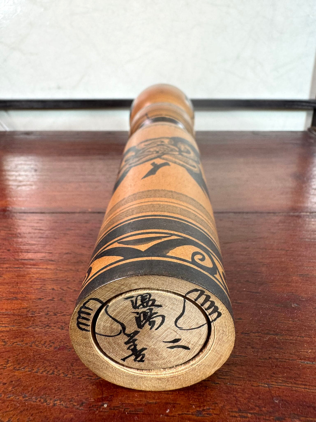 kokeshi poupée japonaise en bois motif pivoine en noir et blanc de Sato Zenji, les pieds dessinés au dessous et la signature de l'artisan