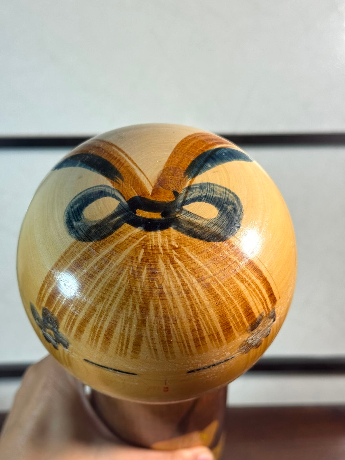 kokeshi, poupée japonaise en bois de Usuki Hakuho bleue avec motif branche de prunier en fleur,, la coiffure avec petit noeud vu de dessus 