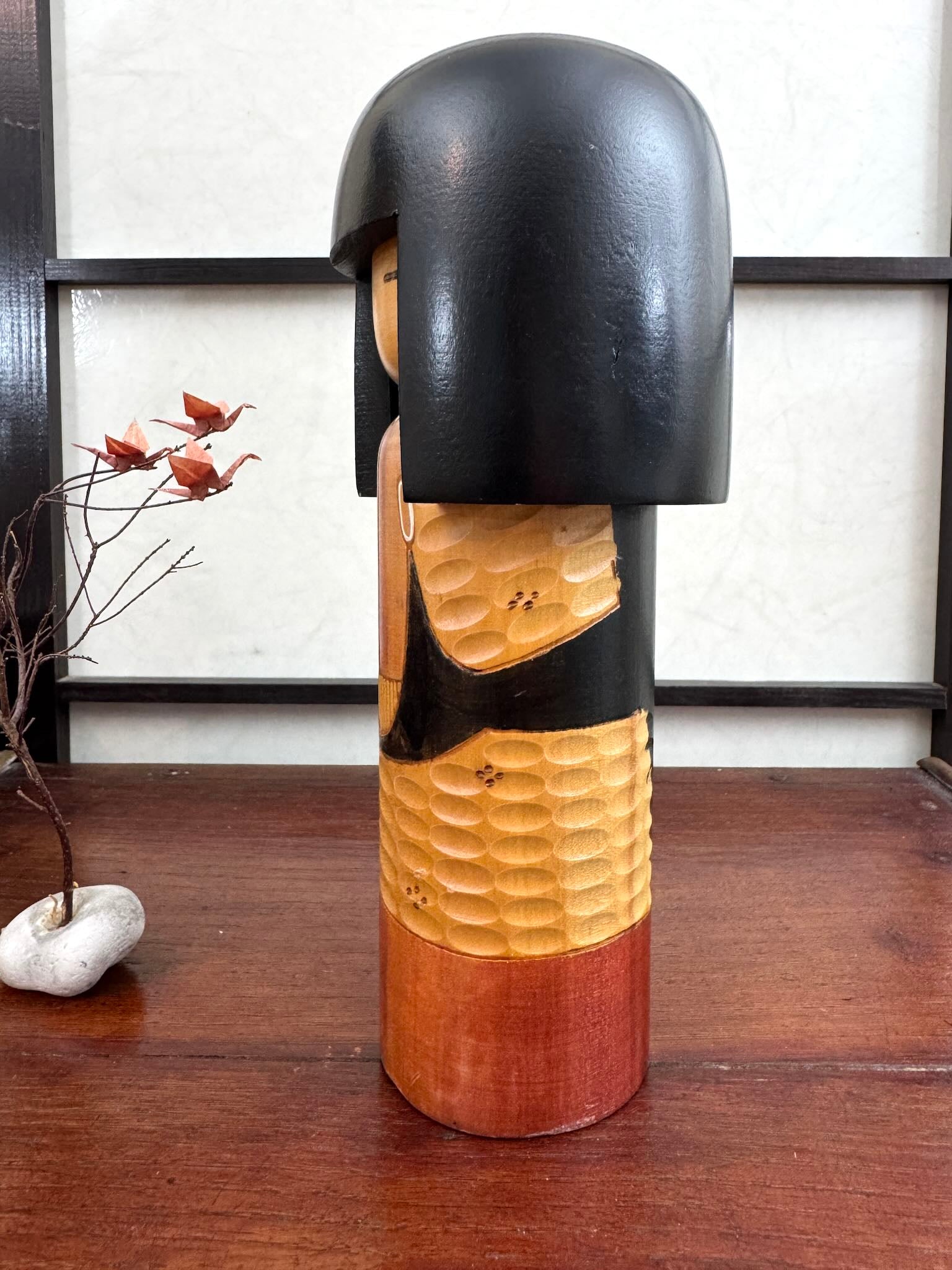 Kokeshi vintage Shinonome de Kisaku avec kimono sculpté en relief et coiffure noire, vu du profil gauche