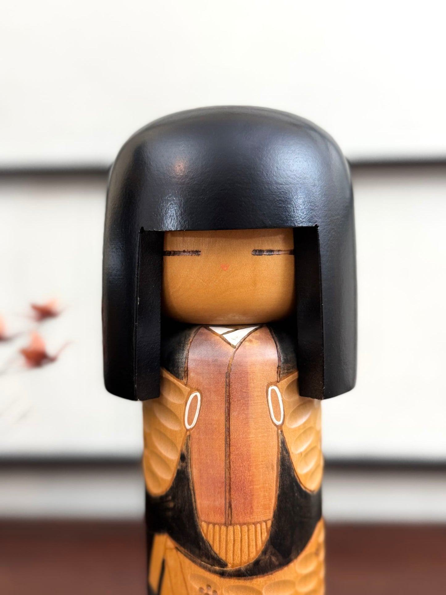 Kokeshi vintage Shinonome de Kisaku avec kimono sculpté en relief et coiffure noire, le visage.