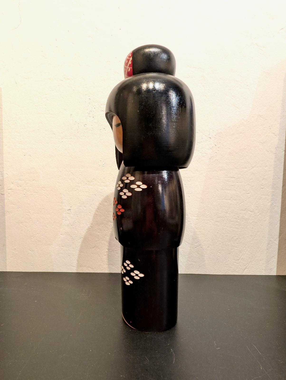kokeshi de Kunio Miyagawa, kimono noir avec fleurs de cerisier rouges et blanches, profil gauche
