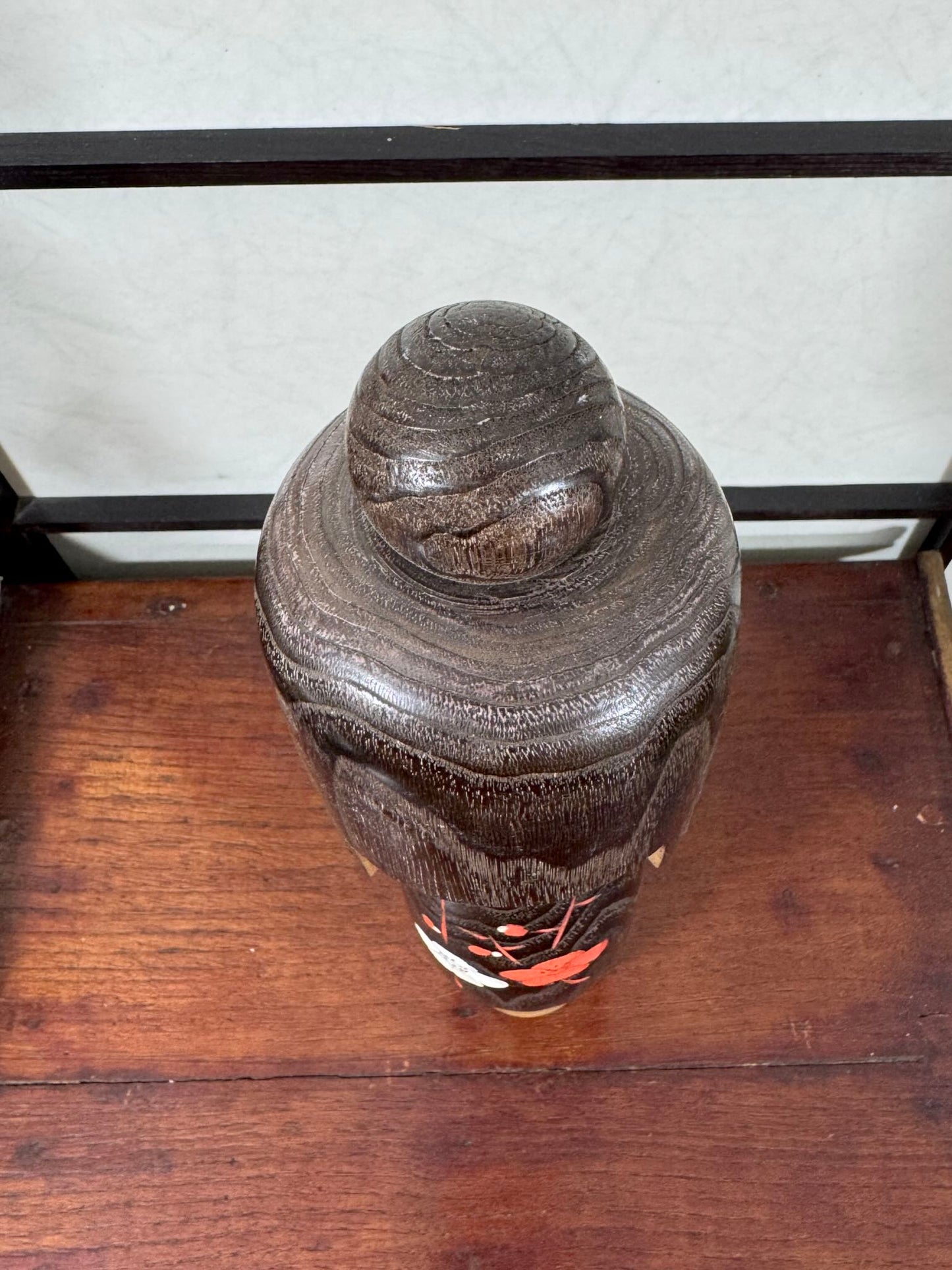 Grande kokeshi Usaburō Koigokoro en bois sombre avec fleurs de prunier rouges et blanches, vu de dessus