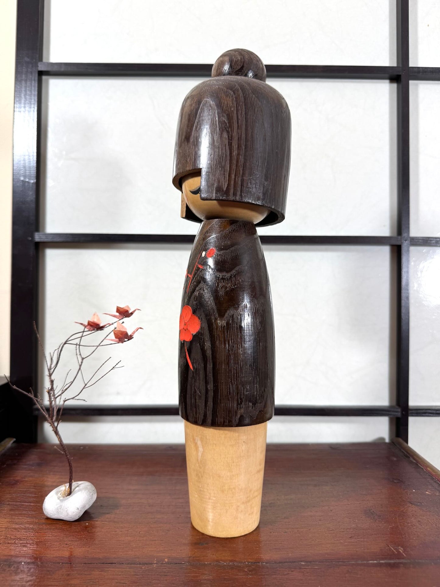 Grande kokeshi Usaburō Koigokoro en bois sombre avec fleurs de prunier rouges et blanches, vu du profil gauche