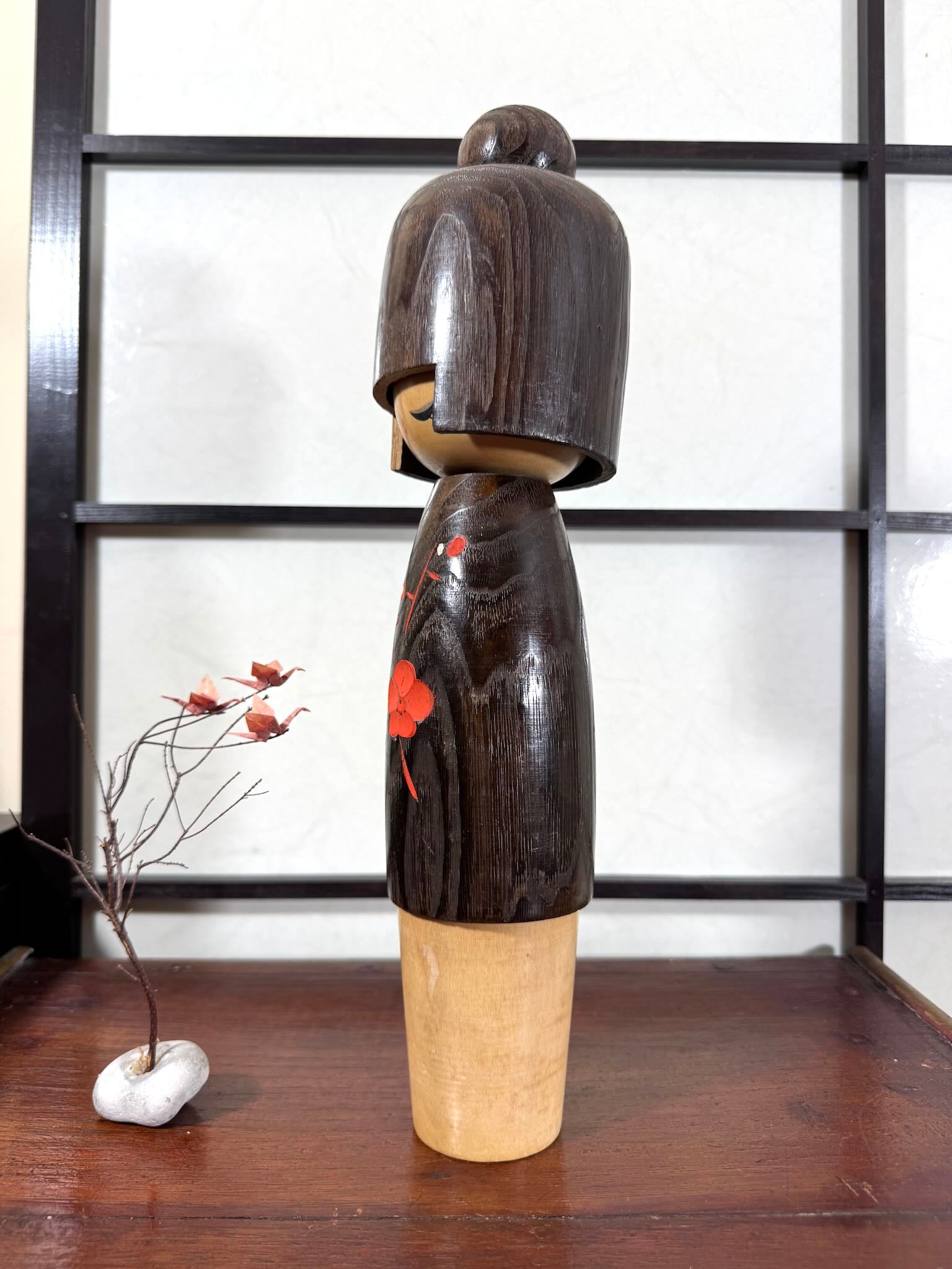 Grande kokeshi Usaburō Koigokoro en bois sombre avec fleurs de prunier rouges et blanches, vu du profil gauche