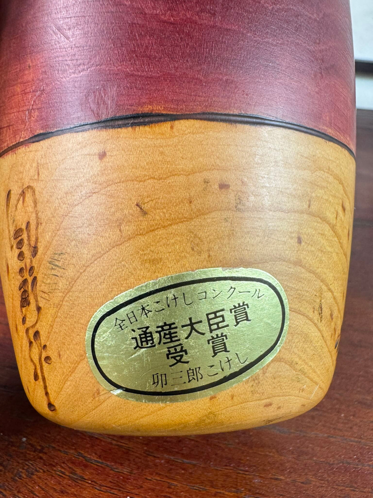 Kokeshi vintage Usaburō de 25 cm ornée de camélias rouges, gros plan sur étiquette kokeshi primée