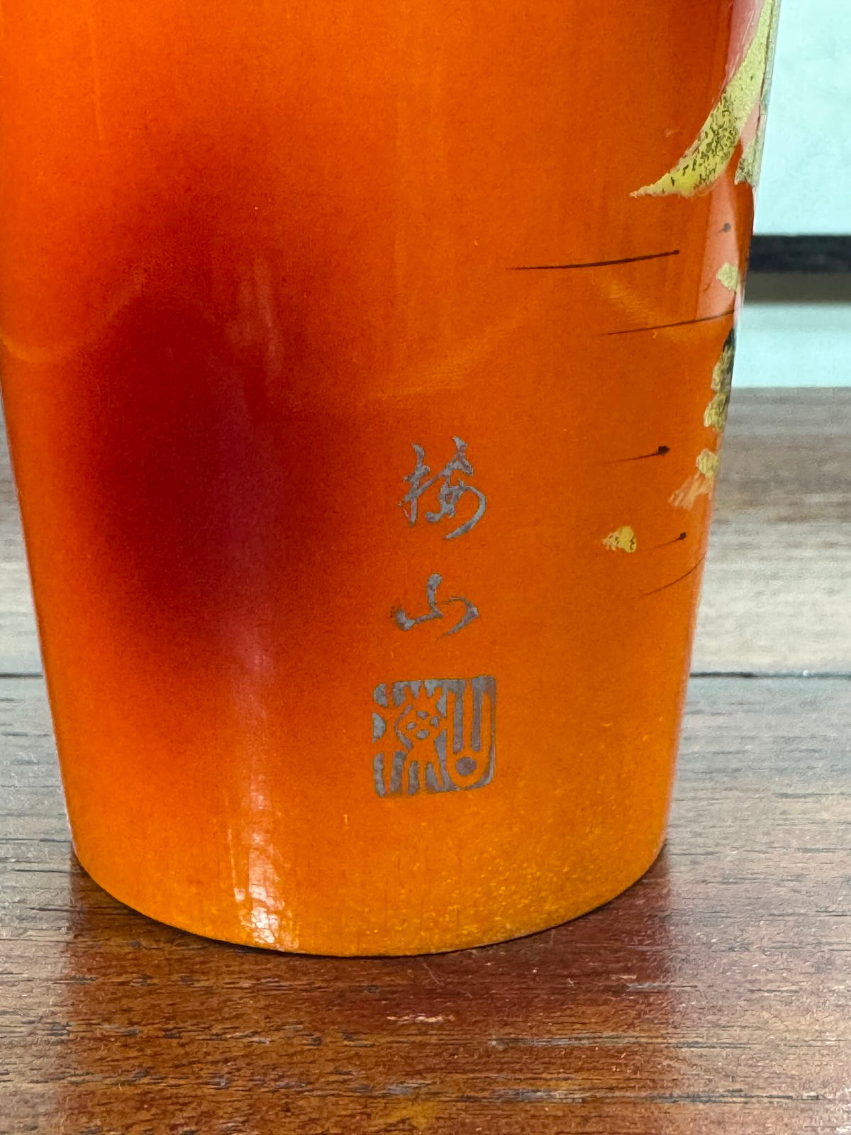 Kokeshi vintage laquée orange de Wajima à paysage japonais doré, gros plan sur le sceau de l'artisan et le nom de la ville de ajima