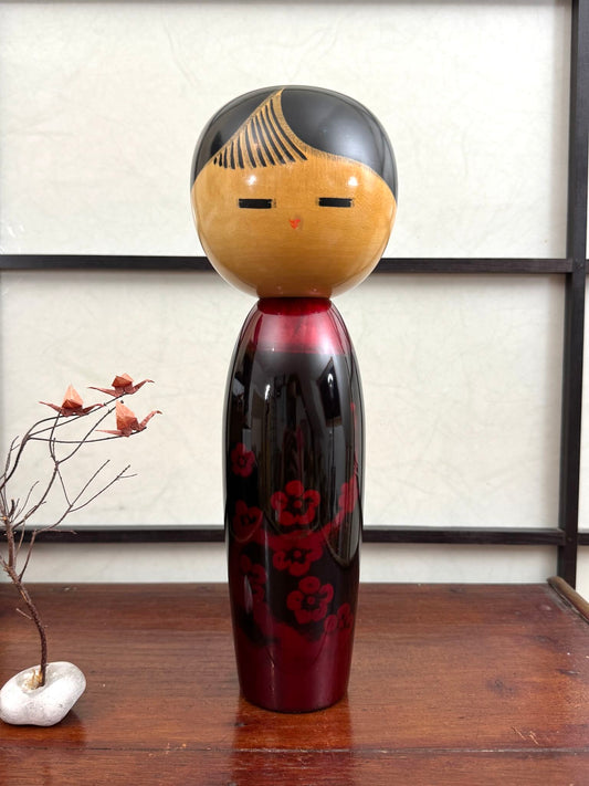 Kokeshi vintage de Sato Norio en laque noire et rouge avec branche de prunier en fleurs, vu de face