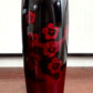 Kokeshi vintage de Sato Norio en laque noire et rouge avec branche de prunier en fleurs, gros plan sur le corps laqué