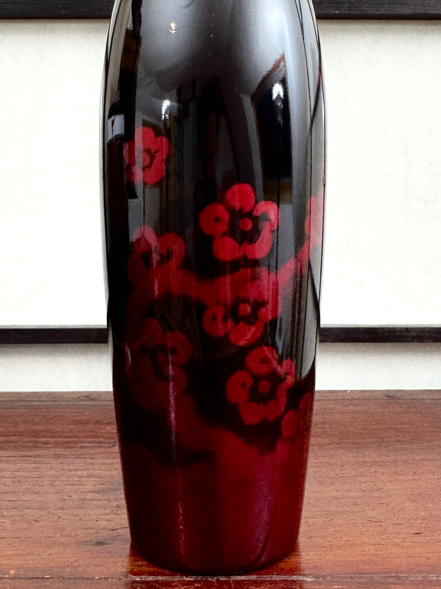 Kokeshi vintage de Sato Norio en laque noire et rouge avec branche de prunier en fleurs, gros plan sur le corps laqué