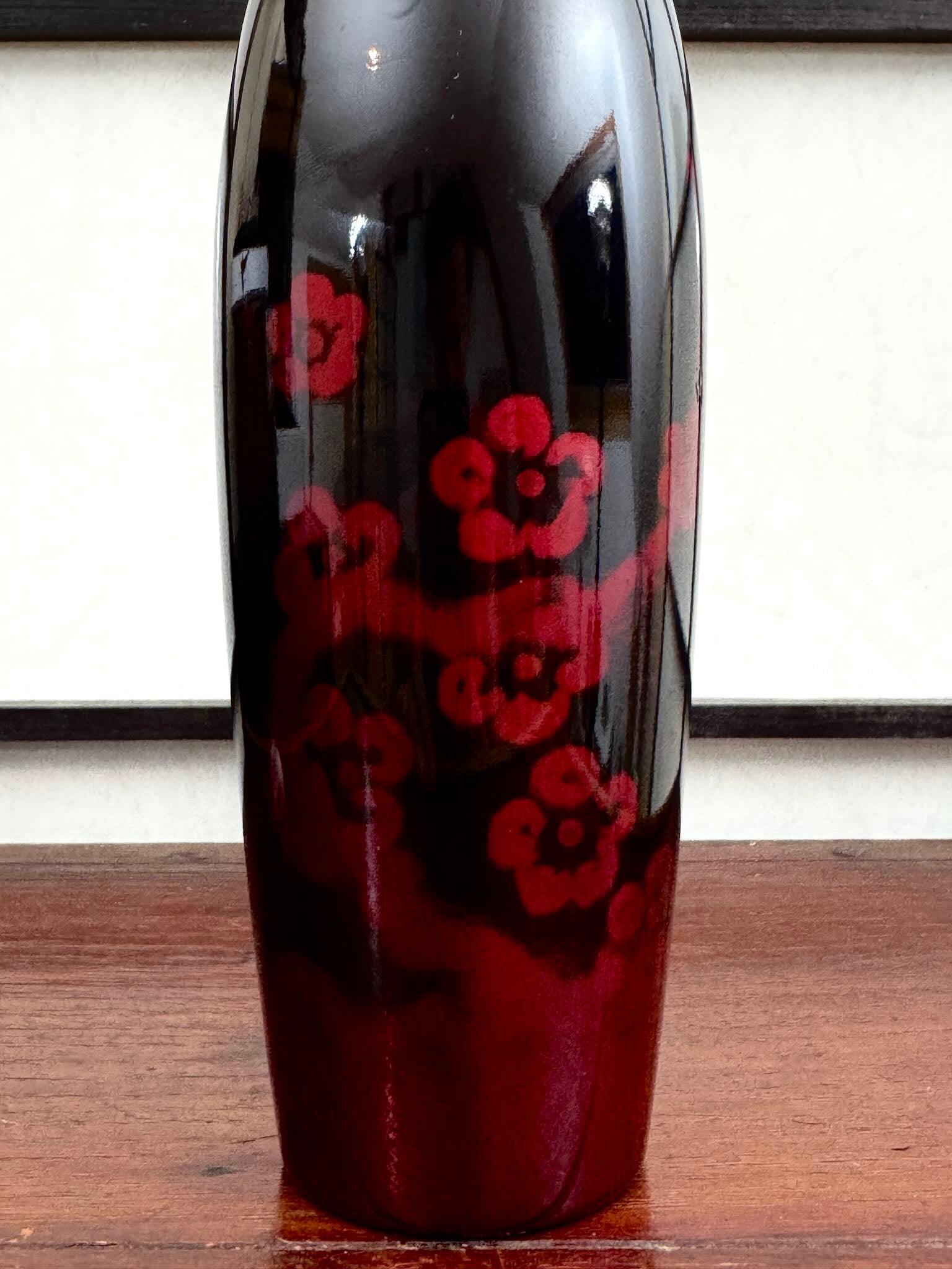 Kokeshi vintage de Sato Norio en laque noire et rouge avec branche de prunier en fleurs, gros plan sur le corps laqué