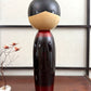 Kokeshi vintage de Sato Norio en laque noire et rouge avec branche de prunier en fleurs, vu de dos