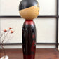 Kokeshi vintage de Sato Norio en laque noire et rouge avec branche de prunier en fleurs, vu du profil droit
