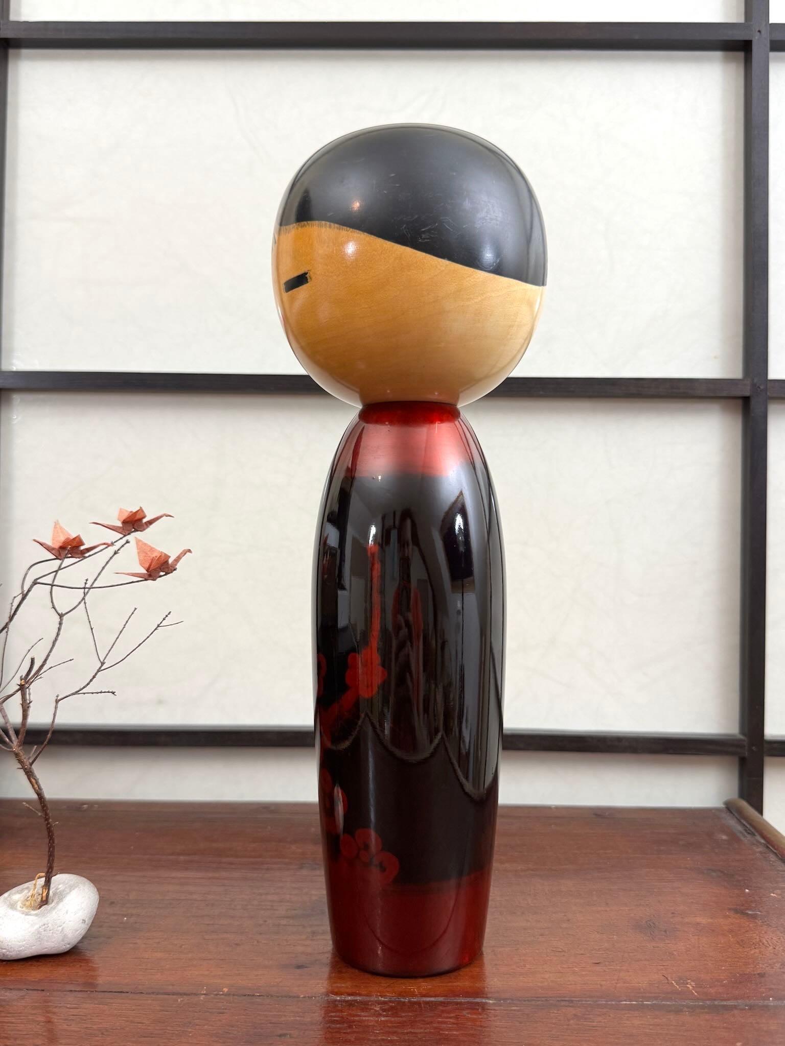 Kokeshi vintage de Sato Norio en laque noire et rouge avec branche de prunier en fleurs, vu du profil gauche