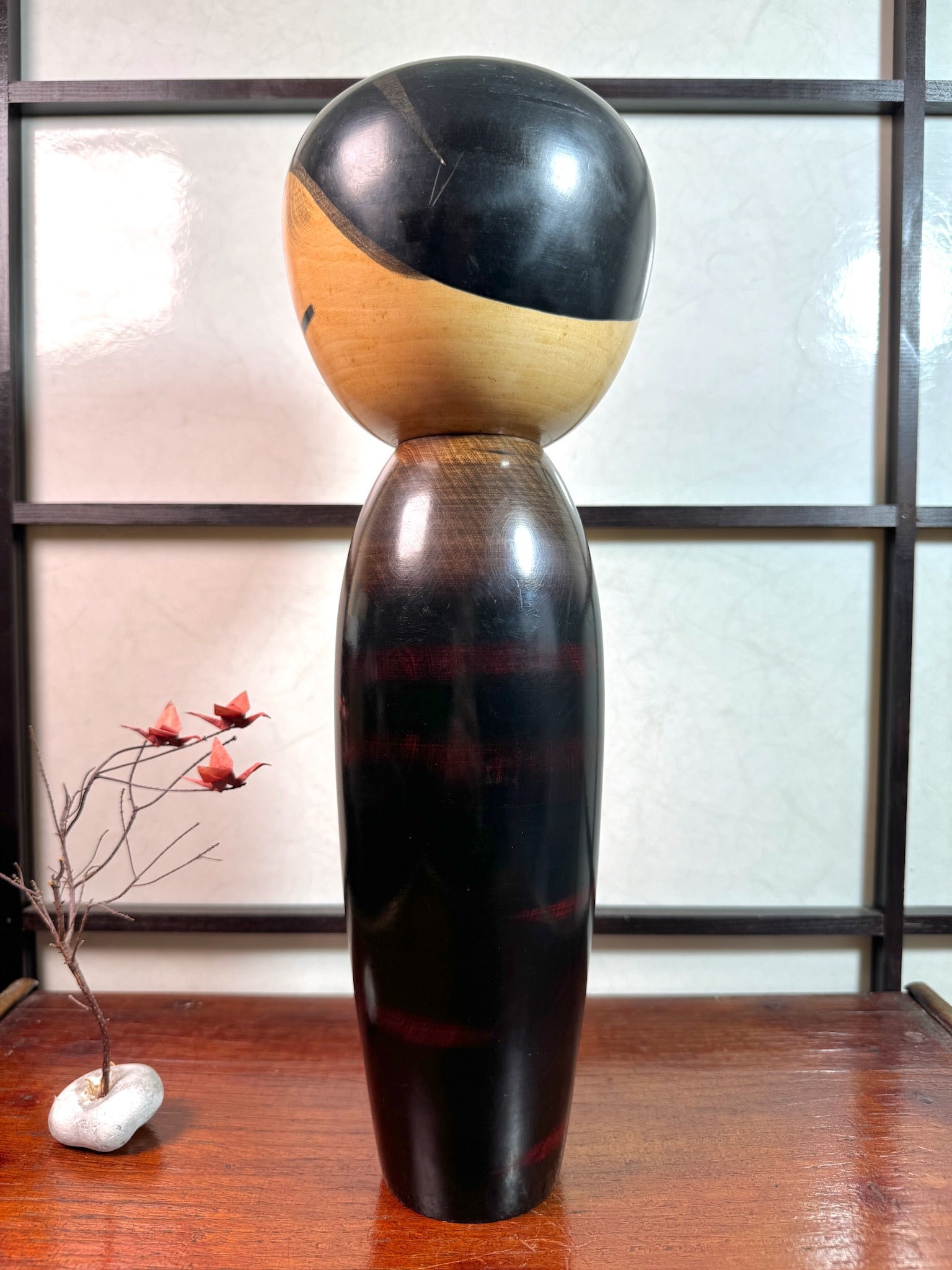 kokeshi de Watanabe Masao, nommé Shigo Sakura, corps laqué reflet rouge évoquant les cerisiers, tête cheveux noir, traits noirs pour les yeux, profil gauche