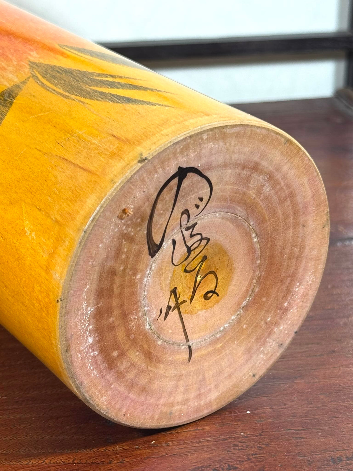 Kokeshi vintage Noboru Tamura jaune à fleurs orange, la signature de l'artisan au dessous