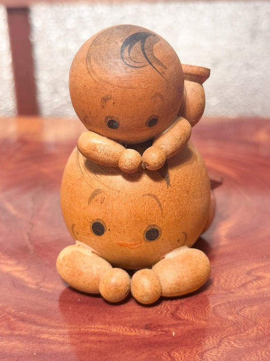 deux kokeshi avec bras et jambes l'une allongé sur le dos de l'autre.