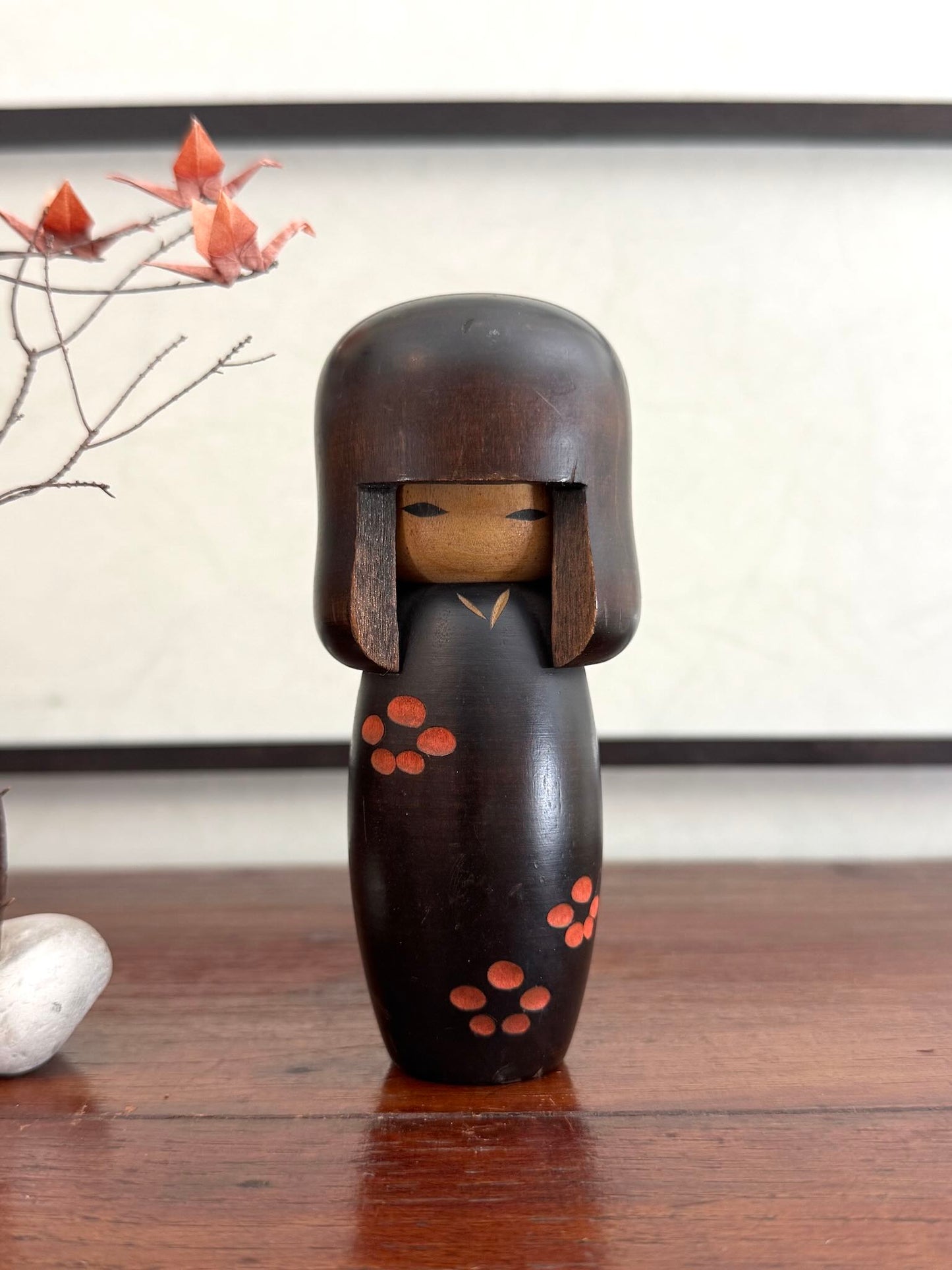 Petite kokeshi Usaburo en bois brun foncé ornée de fleurs de prunier rouge, de face