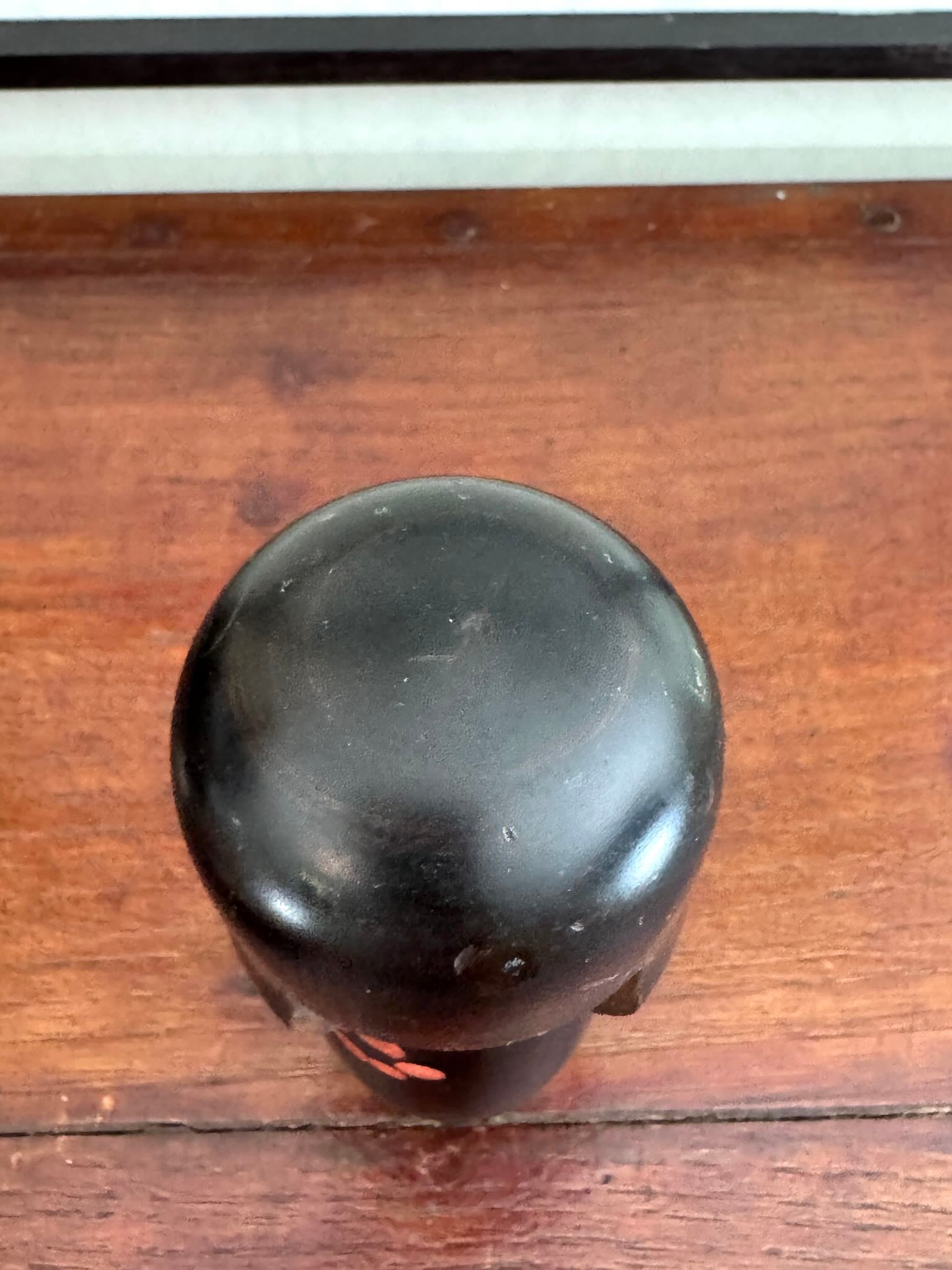 Petite kokeshi Usaburo en bois brun foncé ornée de fleurs de prunier rouge, le dessus