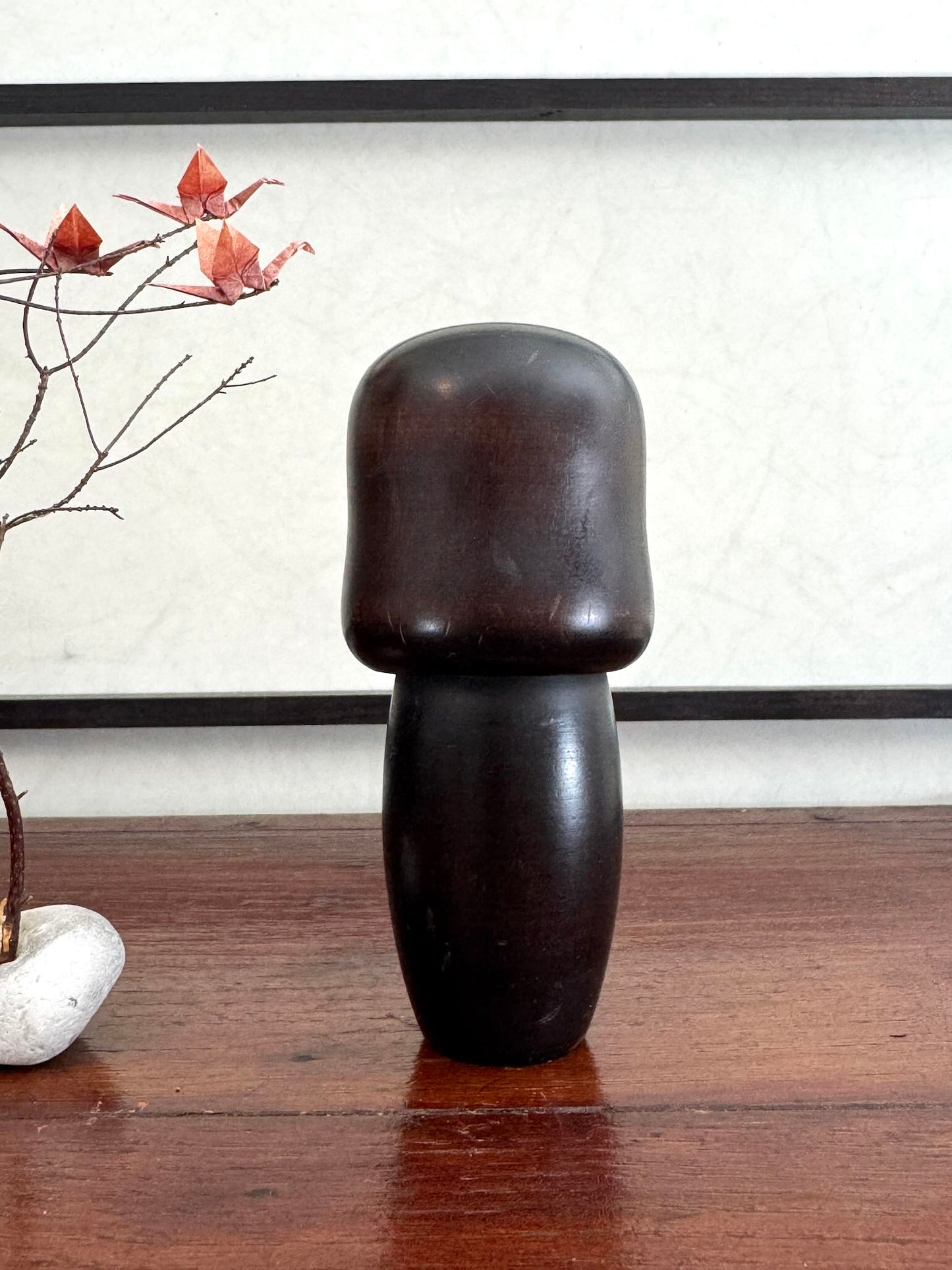 Petite kokeshi Usaburo en bois brun foncé ornée de fleurs de prunier rouge, le dos