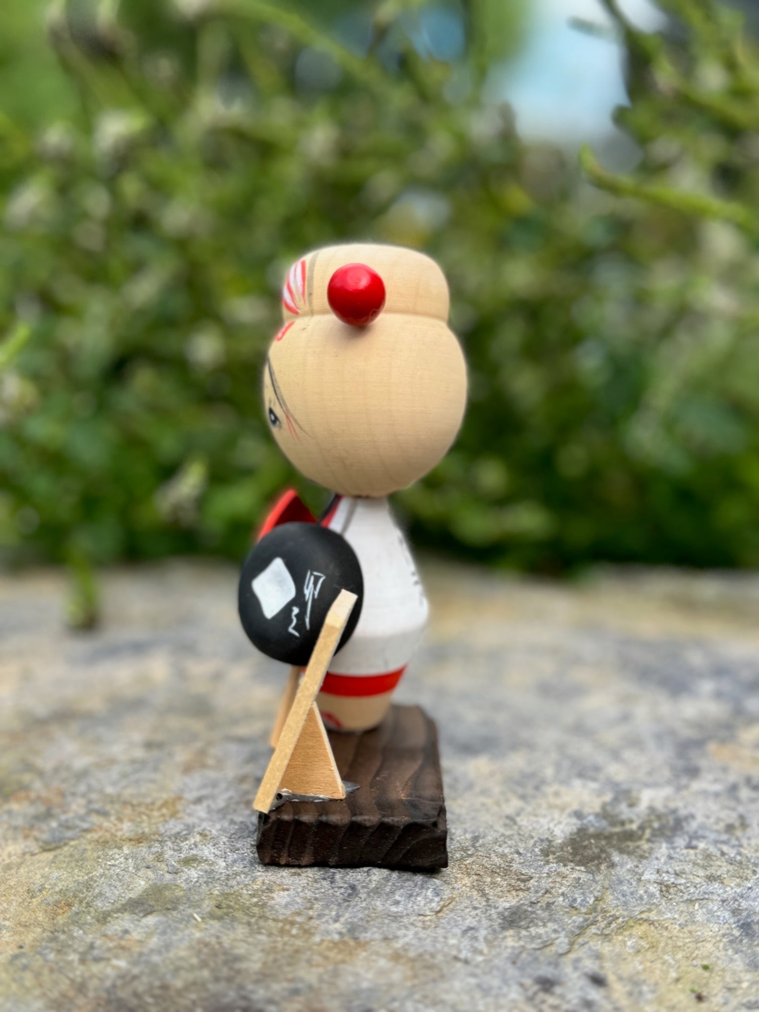 Kokeshi souvenir, poupée en bois japonaise, kimono orange et chapeau noir et blanc, pèlerinage de shikoku, épingle à cheveux rouge ronde, ruban peint et fleurs blanches sur chignon. Poupée de Profil droit, épingle et chapeau. 