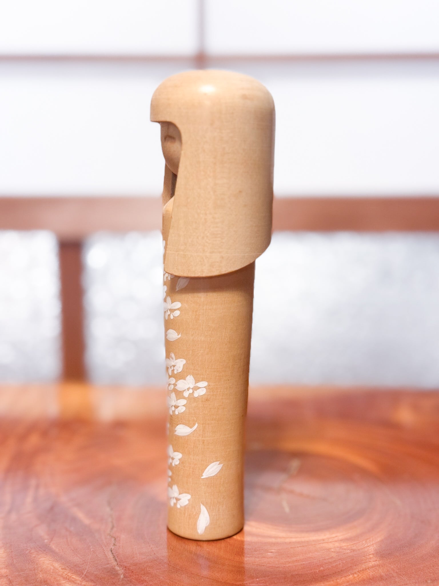 kokeshi de Miyashita Mihutsu en bois naturel avec fleurs blanches peintes et longue chevelure, profil gauche