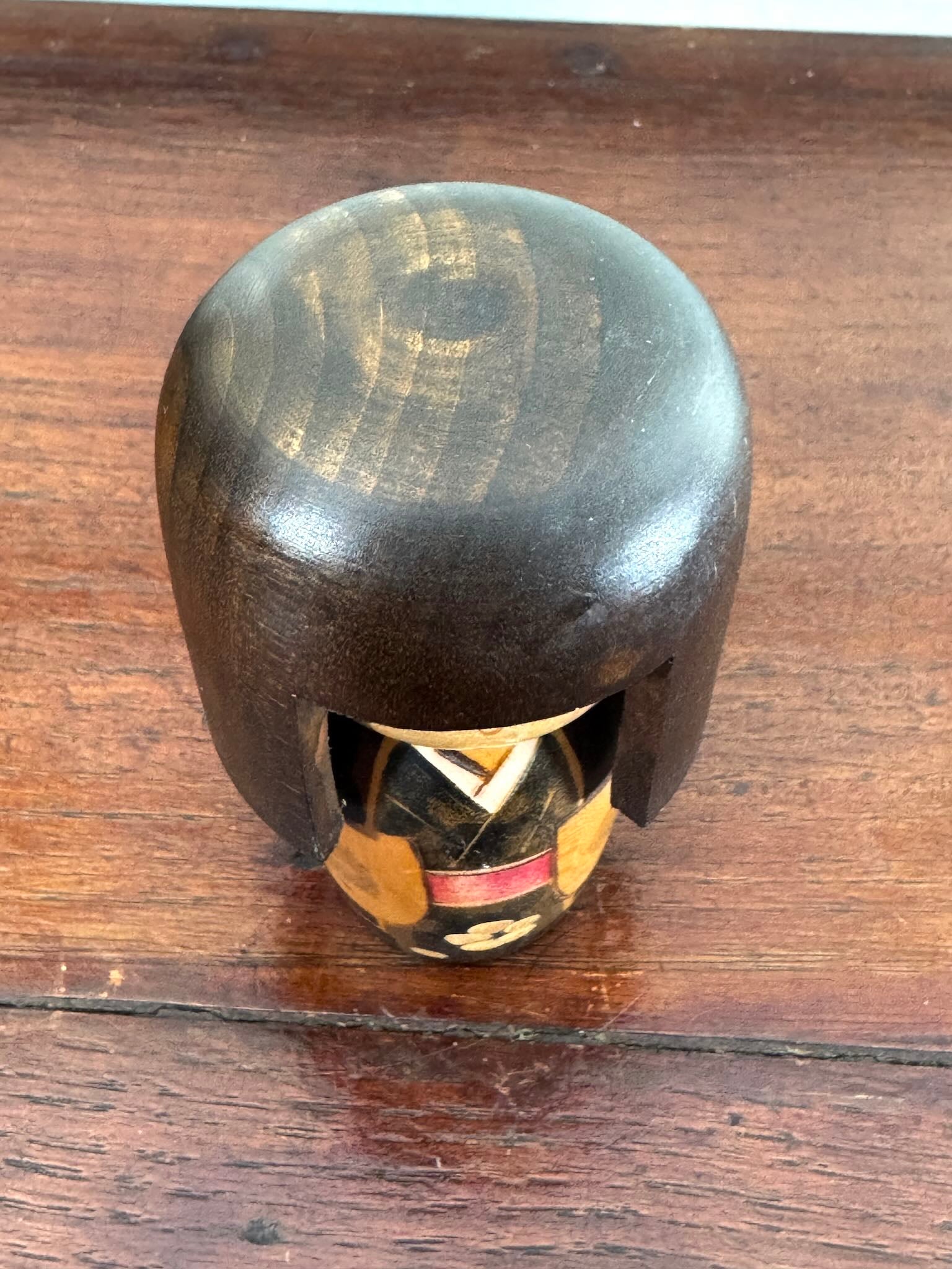Petite kokeshi Gunma Ozawa Shiun en bois avec longue chevelure brune, kimono brun avec fleurs et obi rouge. vue dessus