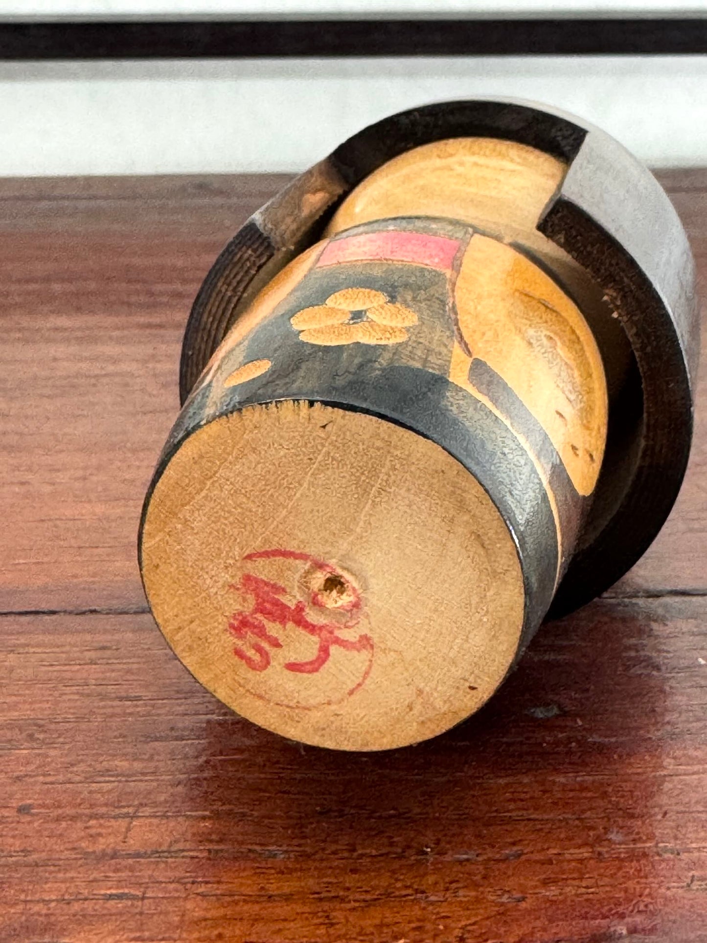 Petite kokeshi Gunma Ozawa Shiun en bois avec longue chevelure brune, kimono brun avec fleurs et obi rouge, sceau artisan dessous