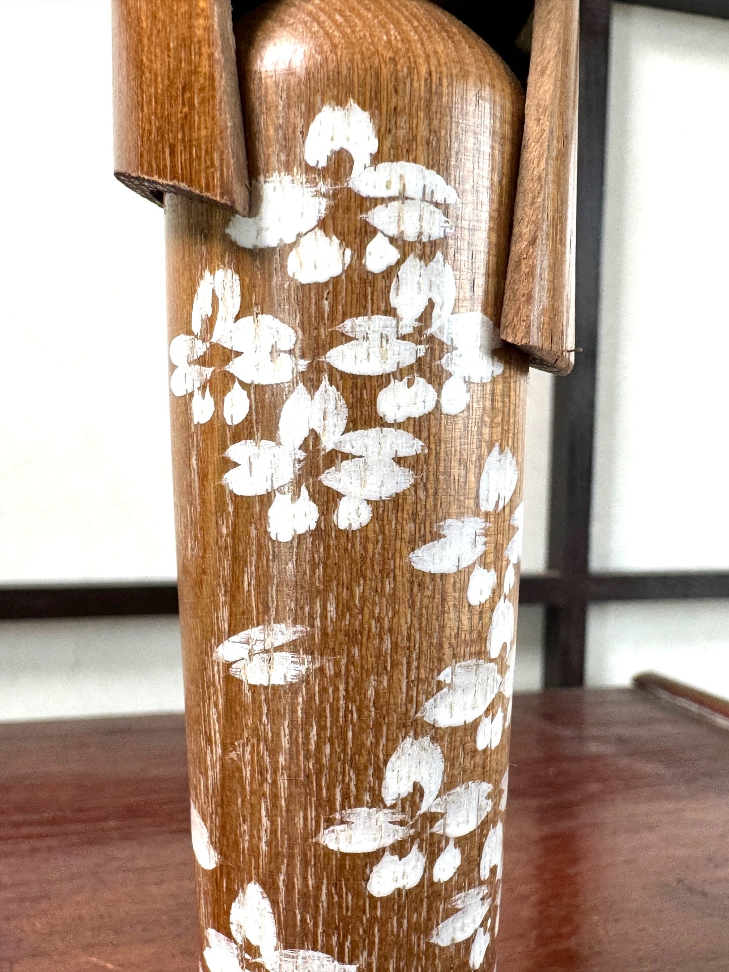 kokeshi, poupée japonaise en bois décoré de fleurs blanches, gros plan sur les fleurs blanches peintes