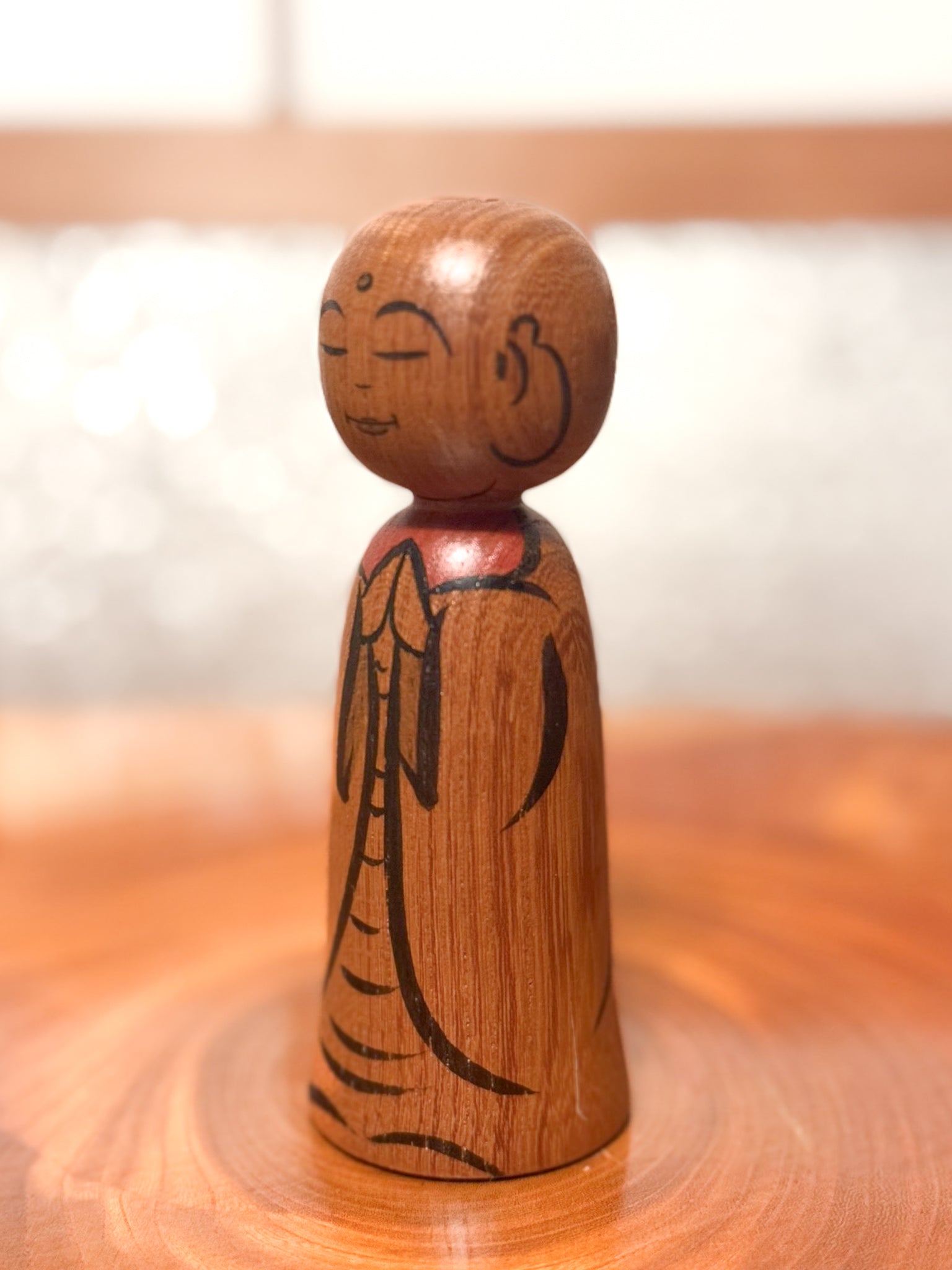kokeshi représentant un jizo mains jointes en prière, profil gauche