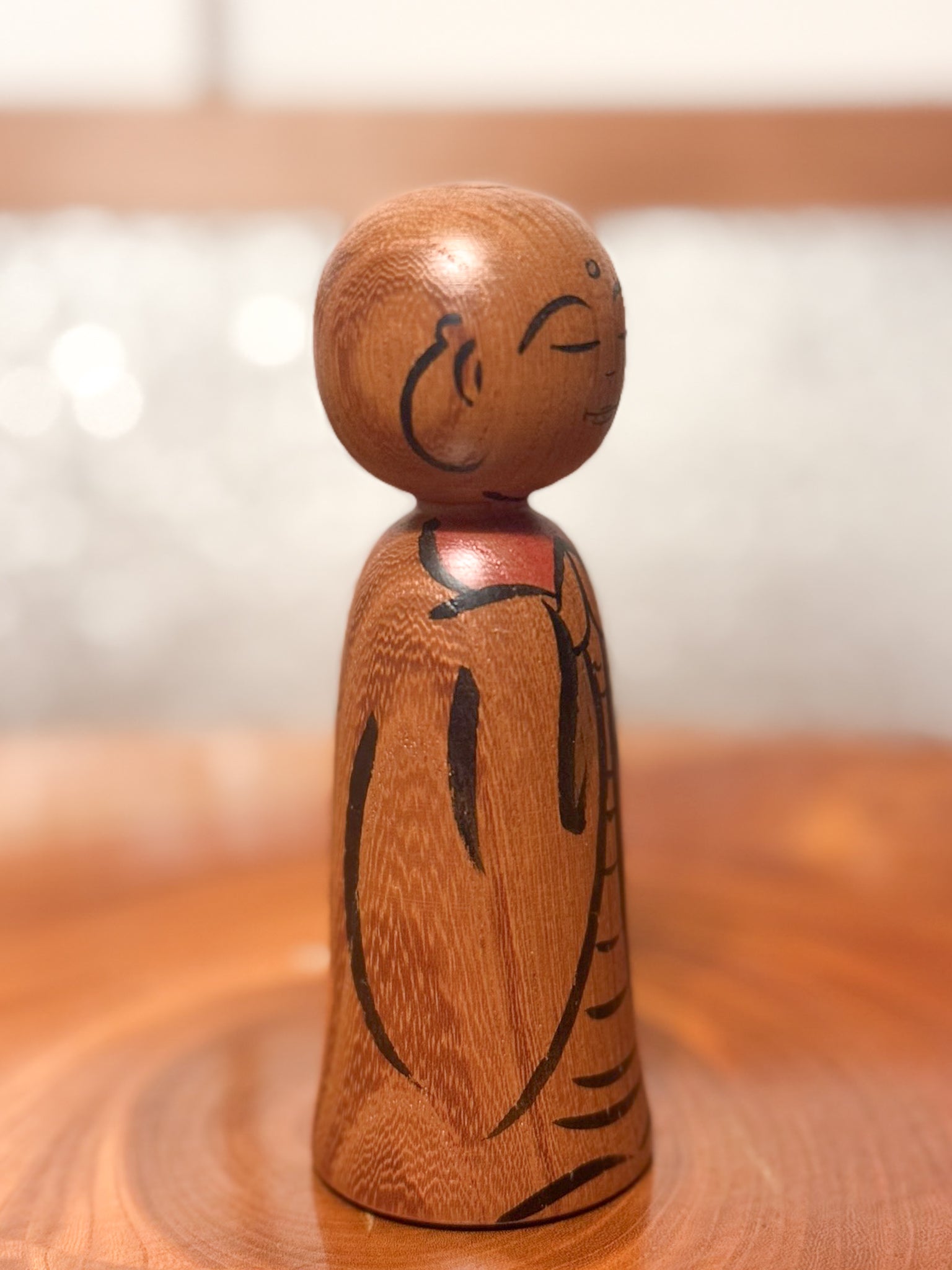 kokeshi représentant un jizo mains jointes en prière, profil droit