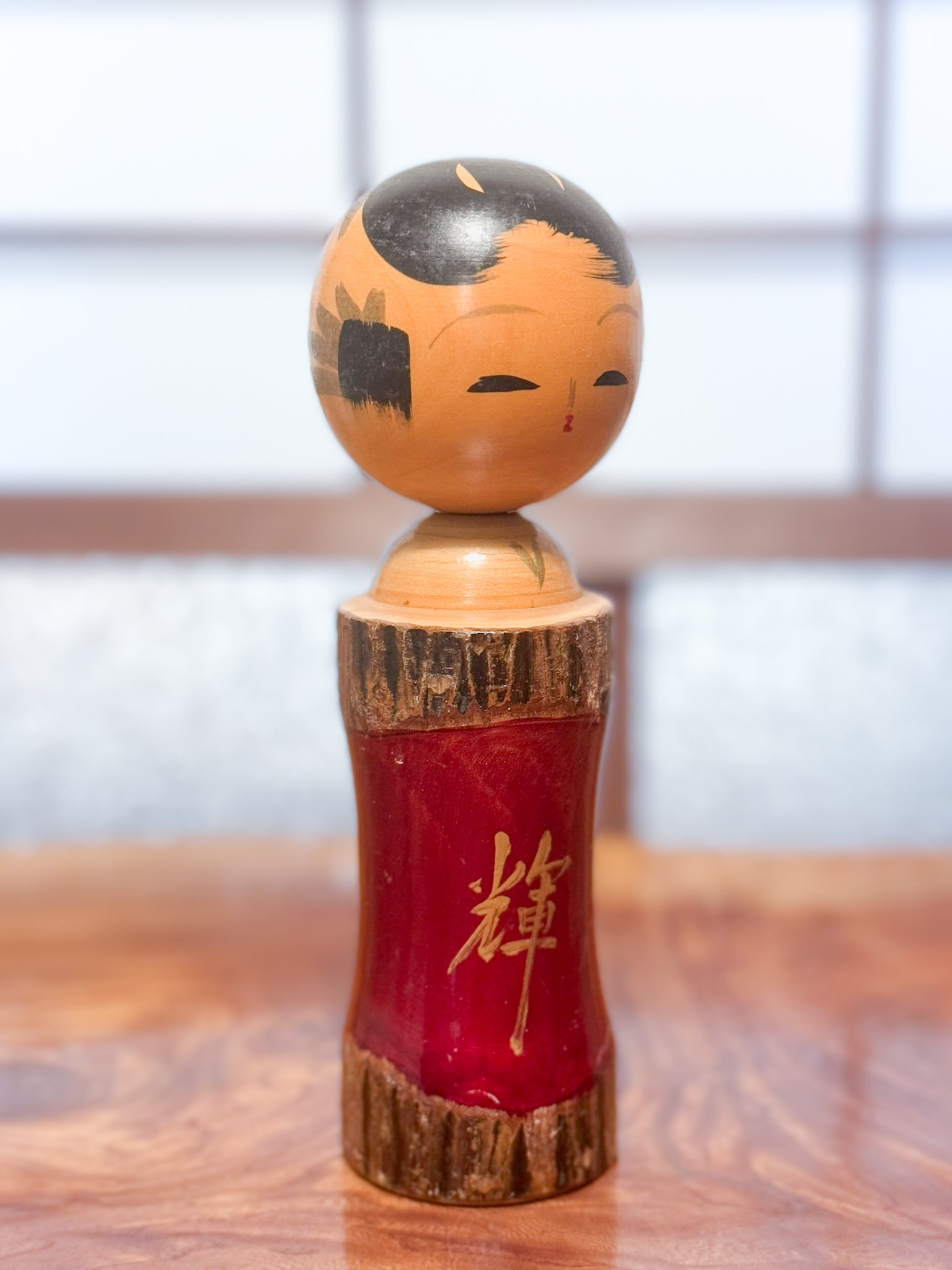 Kokeshi en bois brut avec laque rouge et kanji "zen" doré, vu de 3/4 gauche