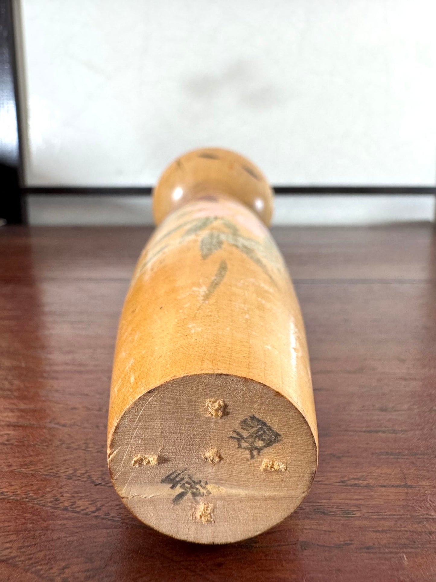 Kokeshi longue en bois avec fleurs peintes a la main, vue dessous