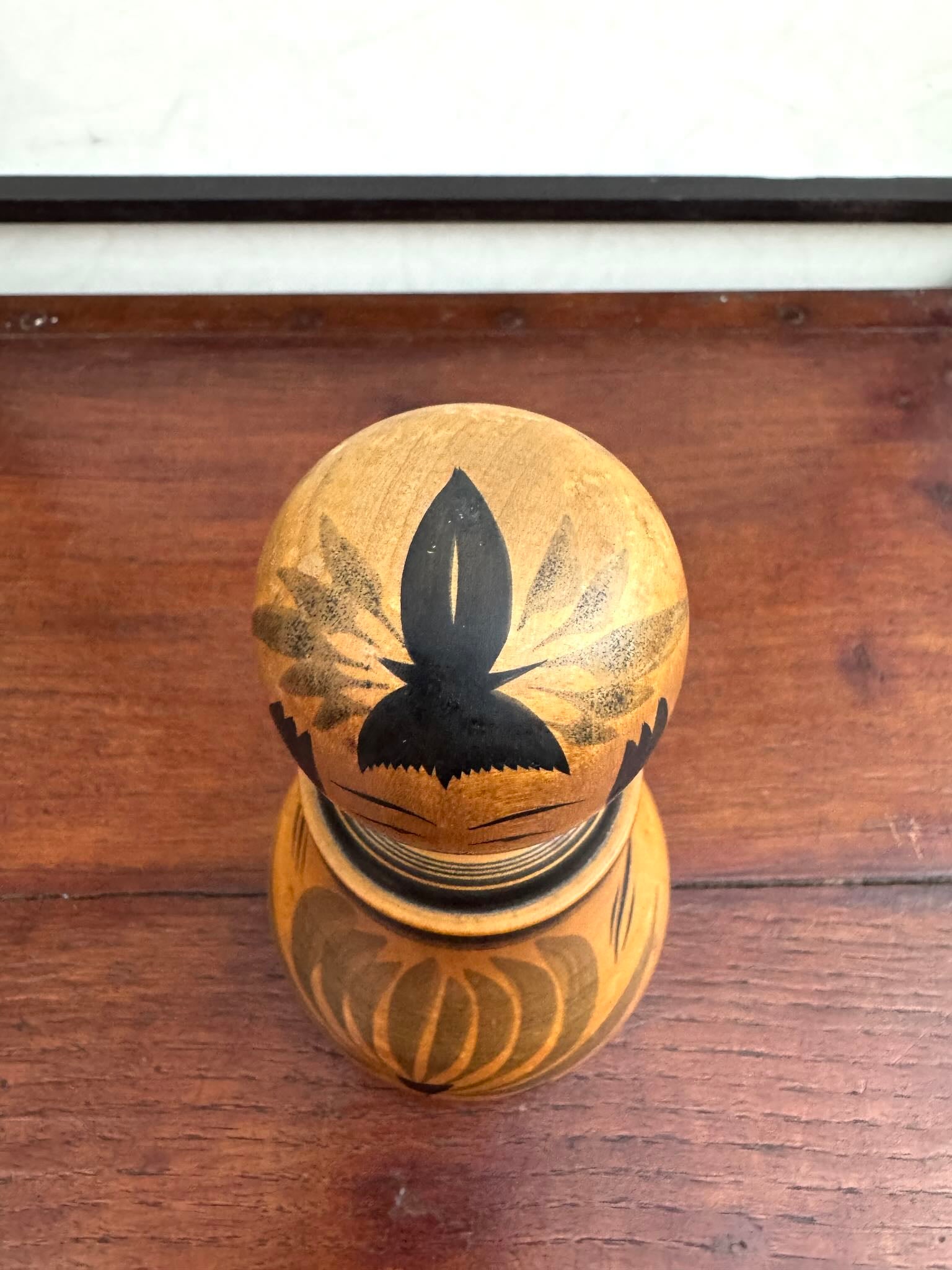 Poupée Japonaise Kokeshi nemariko de Sato Yoshihiro, avec un grand chrysanthème noir peint à la main, vu du dessus