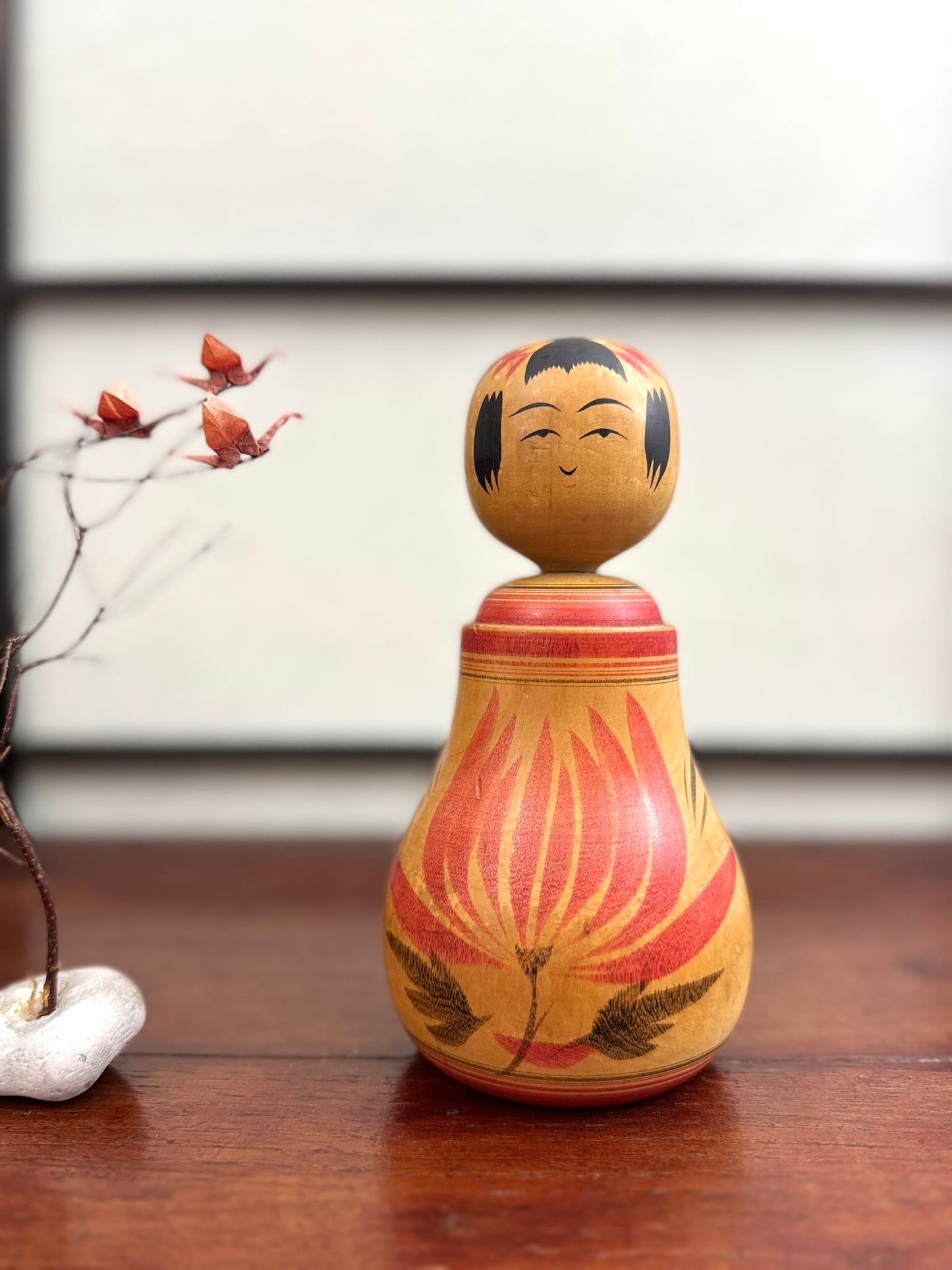 Poupée Japonaise Kokeshi nemariko de Sato Yoshihiro, avec un grand chrysanthème rouge peint à la main, vu de face