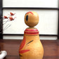 Poupée Japonaise Kokeshi nemariko de Sato Yoshihiro, avec un grand chrysanthème rouge peint à la main, profil gauche