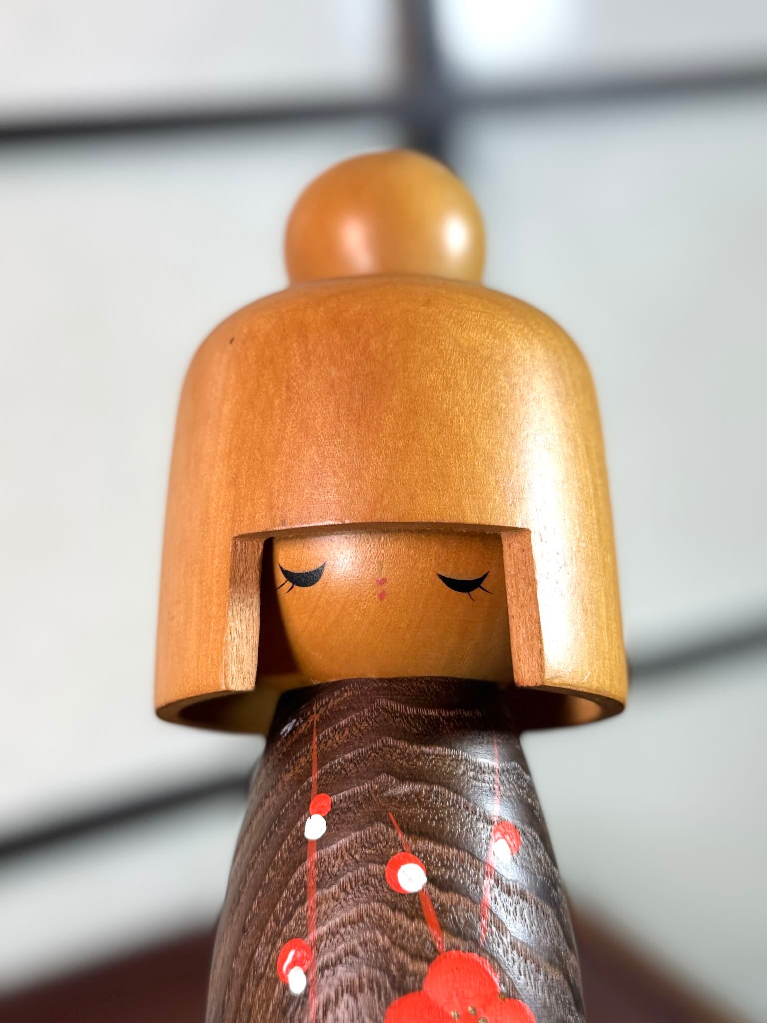 kokeshi, poupée japonaise en bois de Usaburo, avec 3 essences de bois et oif fleur de prunier, gros plan sur la tête